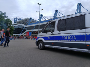 policyjny radiowóz. W tle widać stadion Wisły Kraków oraz tłum kibiców