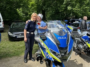 Policjantka i przytulająca się do niej dziewczynka, siedząca na motocyklu.