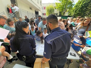 Policjanci przy stoisku profilaktycznym z liczną grupą uczestników.