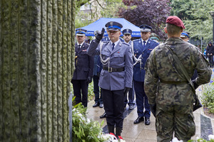 Komendant Wojewódzki Policji w towarzystwie innych mundurowych stoją przed pomnikiem pamięci pomordowanych w hitlerowskich obozach zagłady