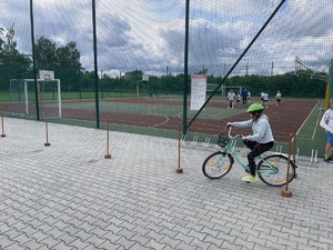 Dziewczynka siedząca na rowerze przejeżdża na torze między tyczkami.