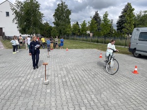 Policjantka nadzoruje przejazd dziewczynki na rowerze po torze.