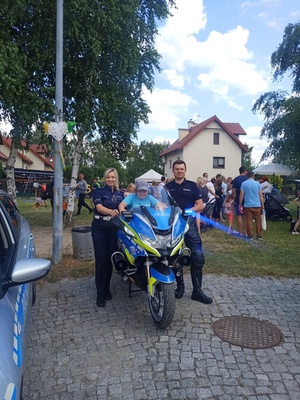 Policjantka i policjant przy motocyklu, na którym siedzi dziecko