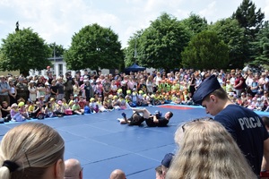 policjanci w trakcie pokazu sprawności fizycznej na macie wokół której zgromadziła się liczna widownia