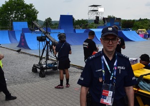 policjant stojący przodem, w tle rampa i skaczący BMX