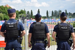 trzech umundurowanych policjantów obserwujących obiekt sportowy krakowskiej Akademii Wychowania Fizycznego