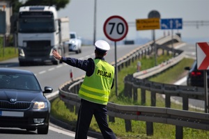 Policjant podczas zatrzymywania pojazdu do kontroli, wskazujący kierowcy miejce do zatrzymania samochodu