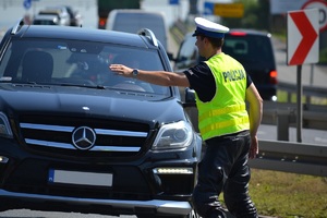 Policjant zatrzymujący do kontroli, wskazujący ręką miejsce do zatrzymania