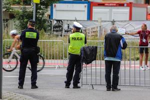 policjant oraz strażnik miejski zabezpieczają trasę na której odbywają się zawody triathlonu