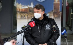 Jarosław Foremny  w czarnej kurtce mówi do mikrofonu w tle rollup sanepidu_1