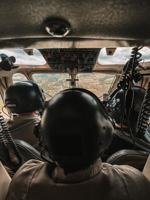 osoby pilotujące śmigłowiec siedzące tyłem do zdjęcia.