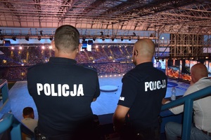 dwóch umundurowanych policjanów stojących tyłem do zdjęcia obserwujących ceremonię zamknięcia igrzysk na obiekcie przy ul. Reymonta