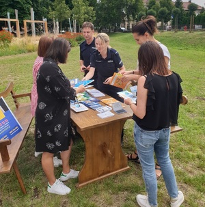 osoby stoją przy policyjnym stoisku profilaktycznym