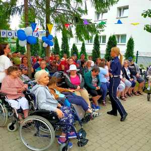 policjantka tłumaczy zasady bezpieczeństwa dla licznych uczestników spotkania w tle budynek