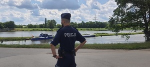 policjant obserwuje nabrzeże rzeki Wisła, w tle rzeka