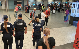 policjanci idą holem dworca kolejowego w tle podróżni