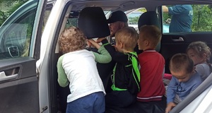 policjant w radiowozie pokazuje grupie dzieci wnetrze pojazdu