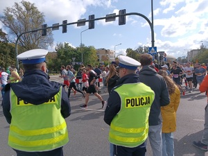 dwóch umundurowanych policjantów obserwujących uczestników biegu