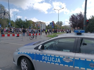 policyjny radiowóz stojący przy jednej z ulic na której widać uczestników biegu
