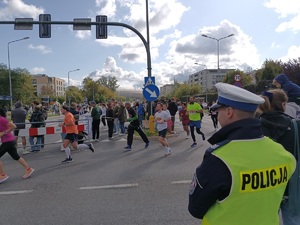 umundurowany policjant obserwujący uczestników biegu na jednej z głównych ulic Krakowa