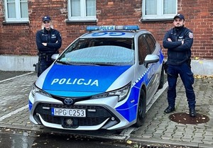 umundurowana policjantka i umundurowany policjant stojący przy oznakowanym radiowozie