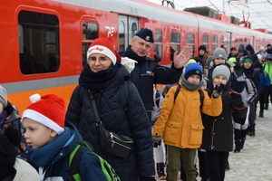 uczniowie wraz z pracownikami funkcjonariuszem policji - w tle zdjęcia pociąg