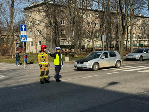 4 strażak w obecności policjantki ćwiczy kierowanie ruchem drogowym na skrzyżowaniu